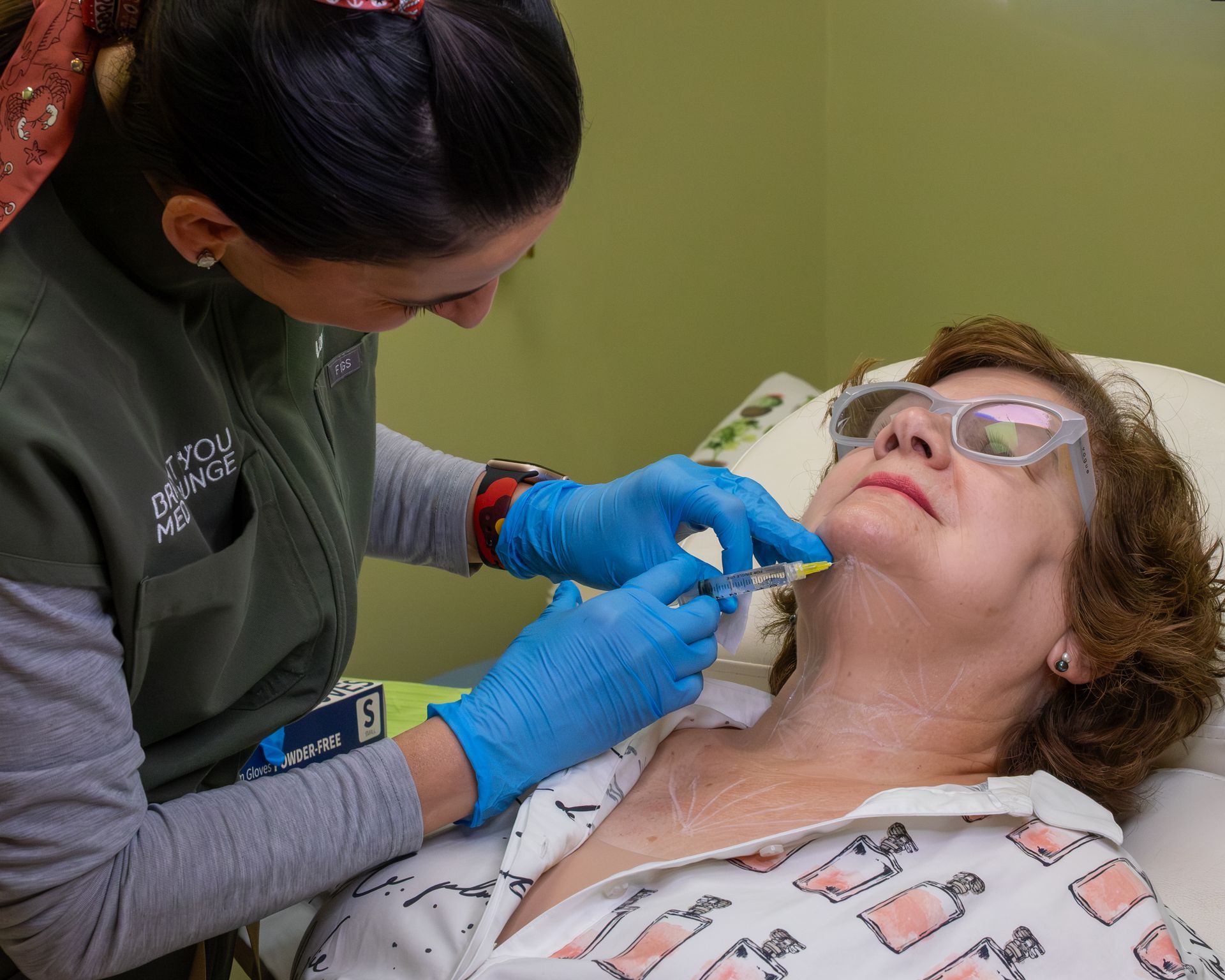 Dental professional examining a patient’s mouth while wearing blue gloves and magnifying glasses