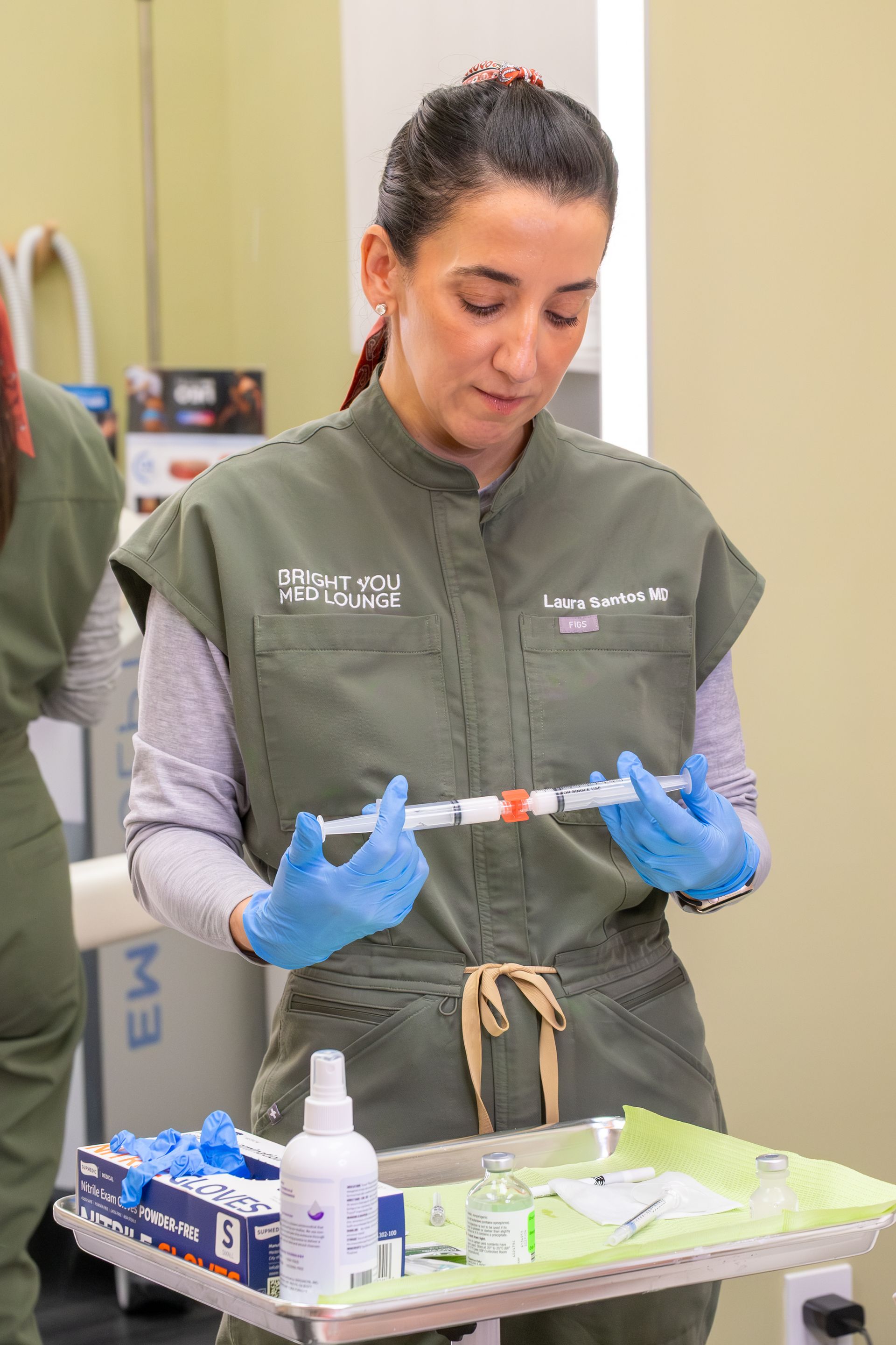 Gloved technician preparing a syringe beside a medical tray in a lab setting