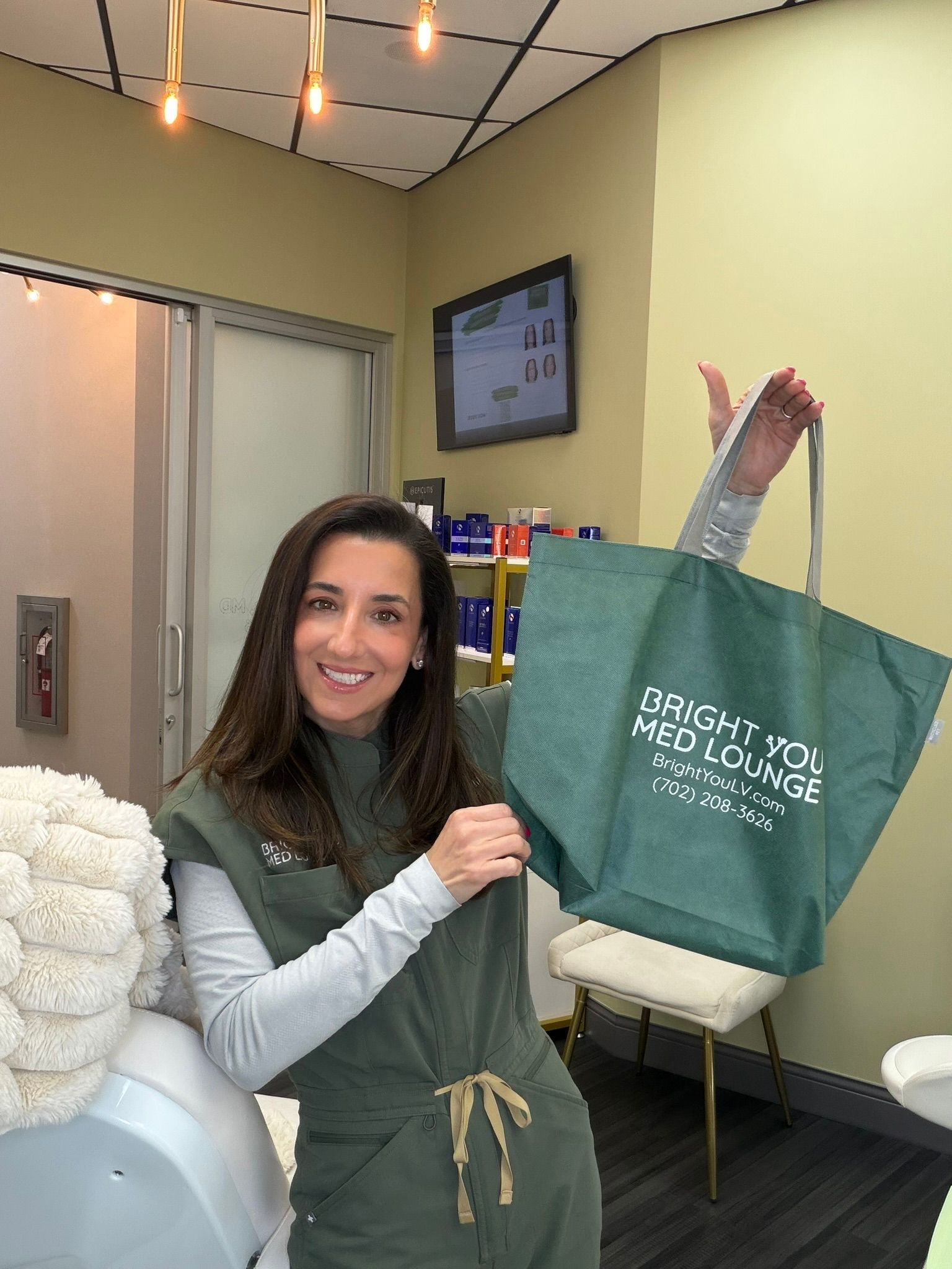 Woman smiling and holding a large green tote bag in a clinic room