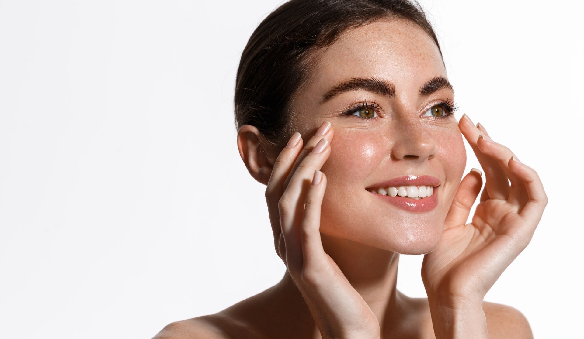 Smiling woman applying cream to her cheeks against a white background