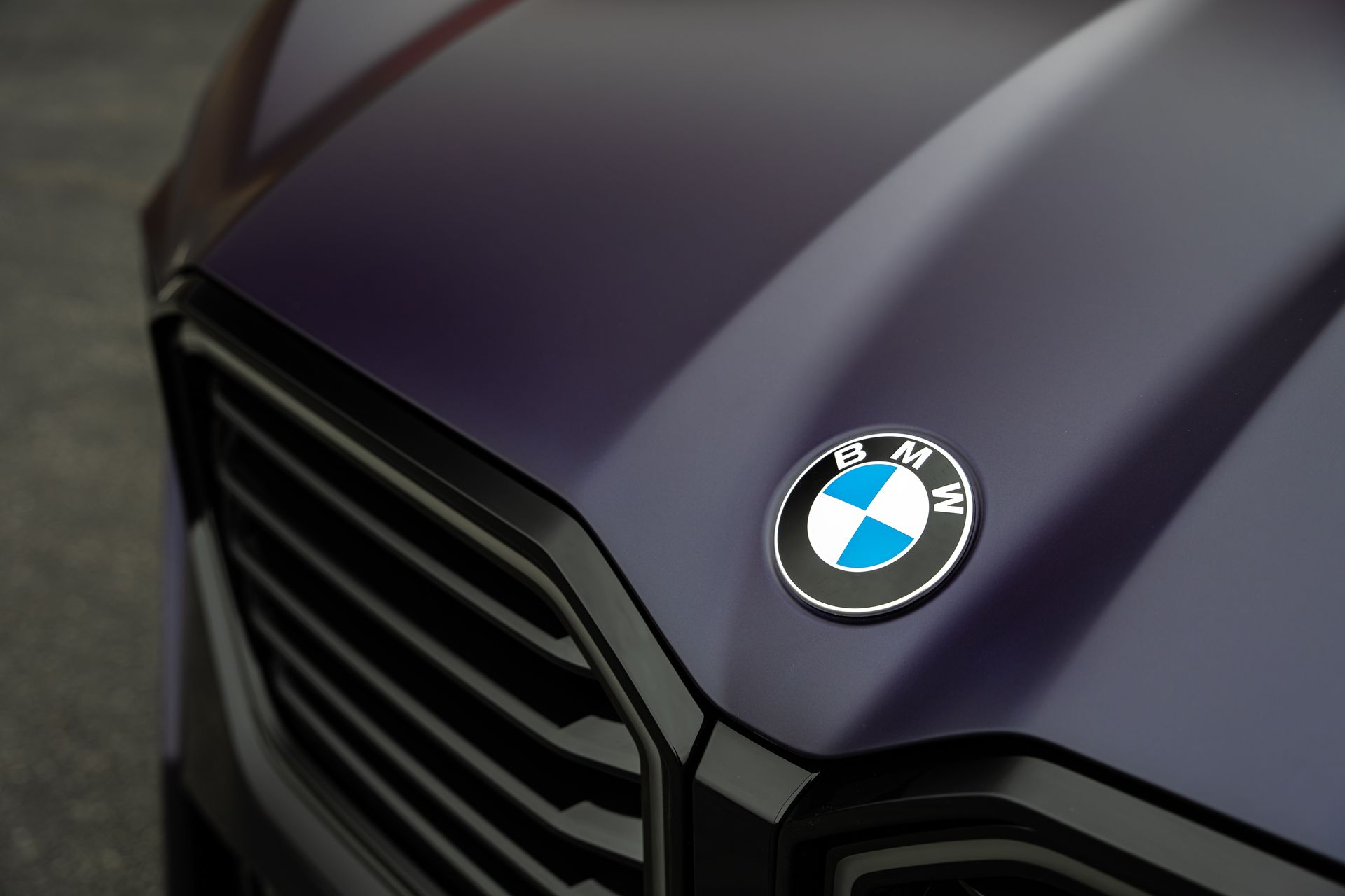 Close-up of a dark purple BMW car hood with the BMW logo above a black grill.