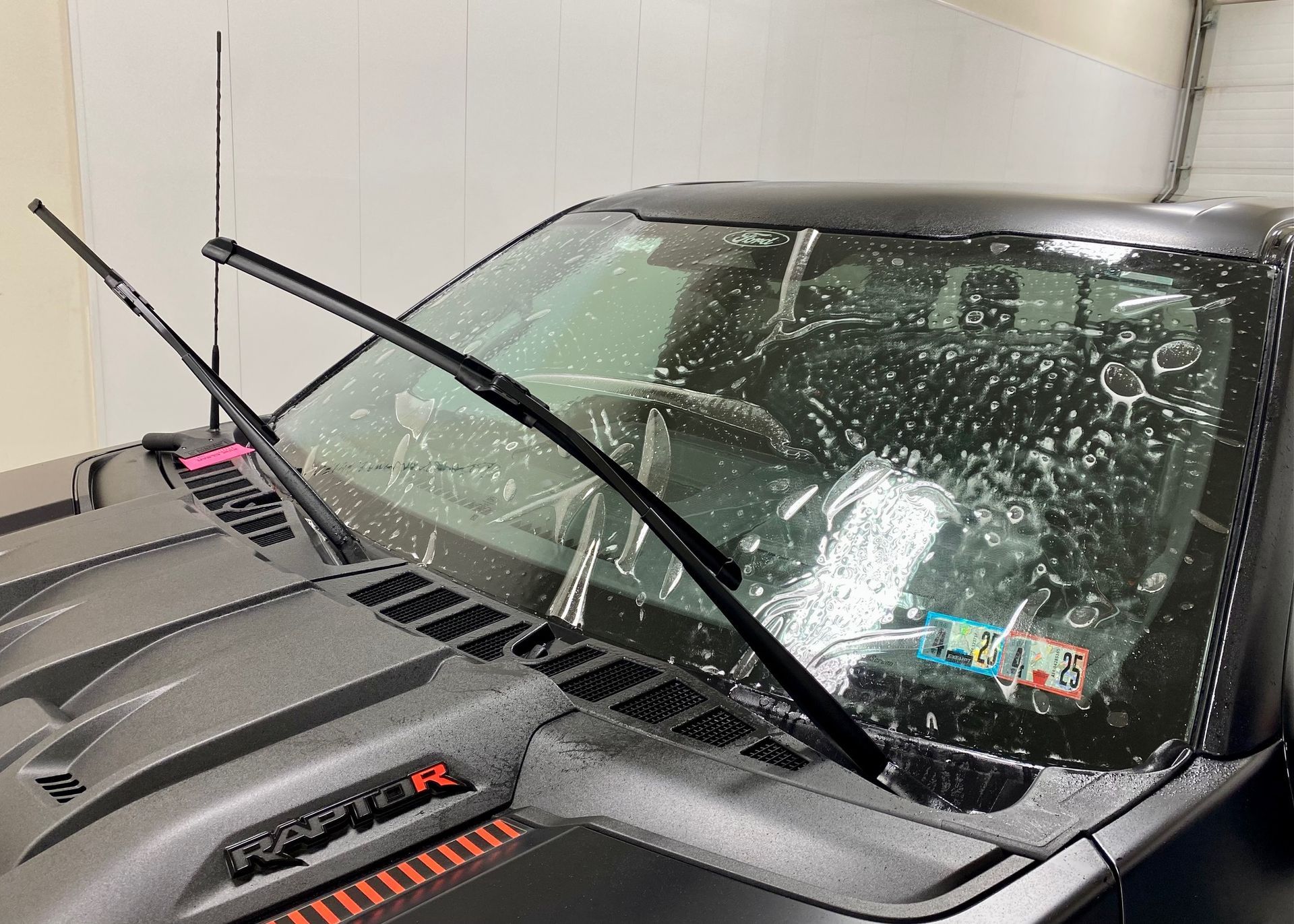 Black truck windshield with soap, wipers extended.