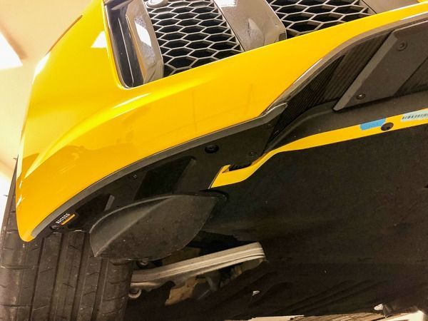Yellow car's underside, revealing a wheel, suspension, and aerodynamic elements.