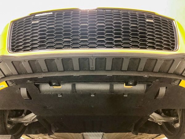 Yellow car's underside view showing the front grill, undercarriage, and suspension.