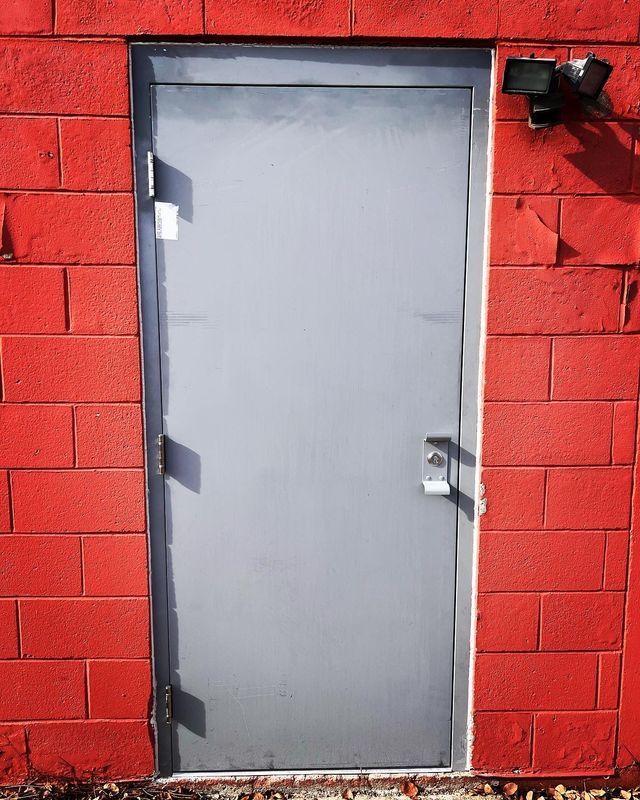 A red brick wall with a gray door
