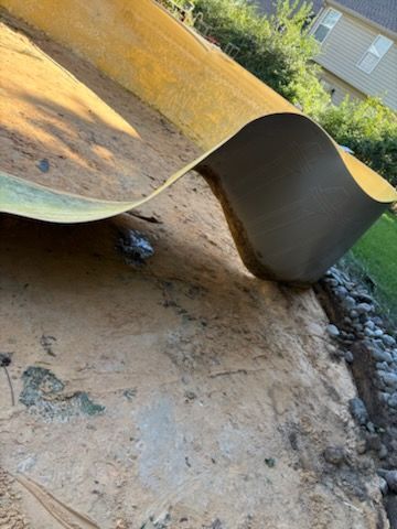 Curved yellow slide ending over a dirt surface, with a small gap and building in the background