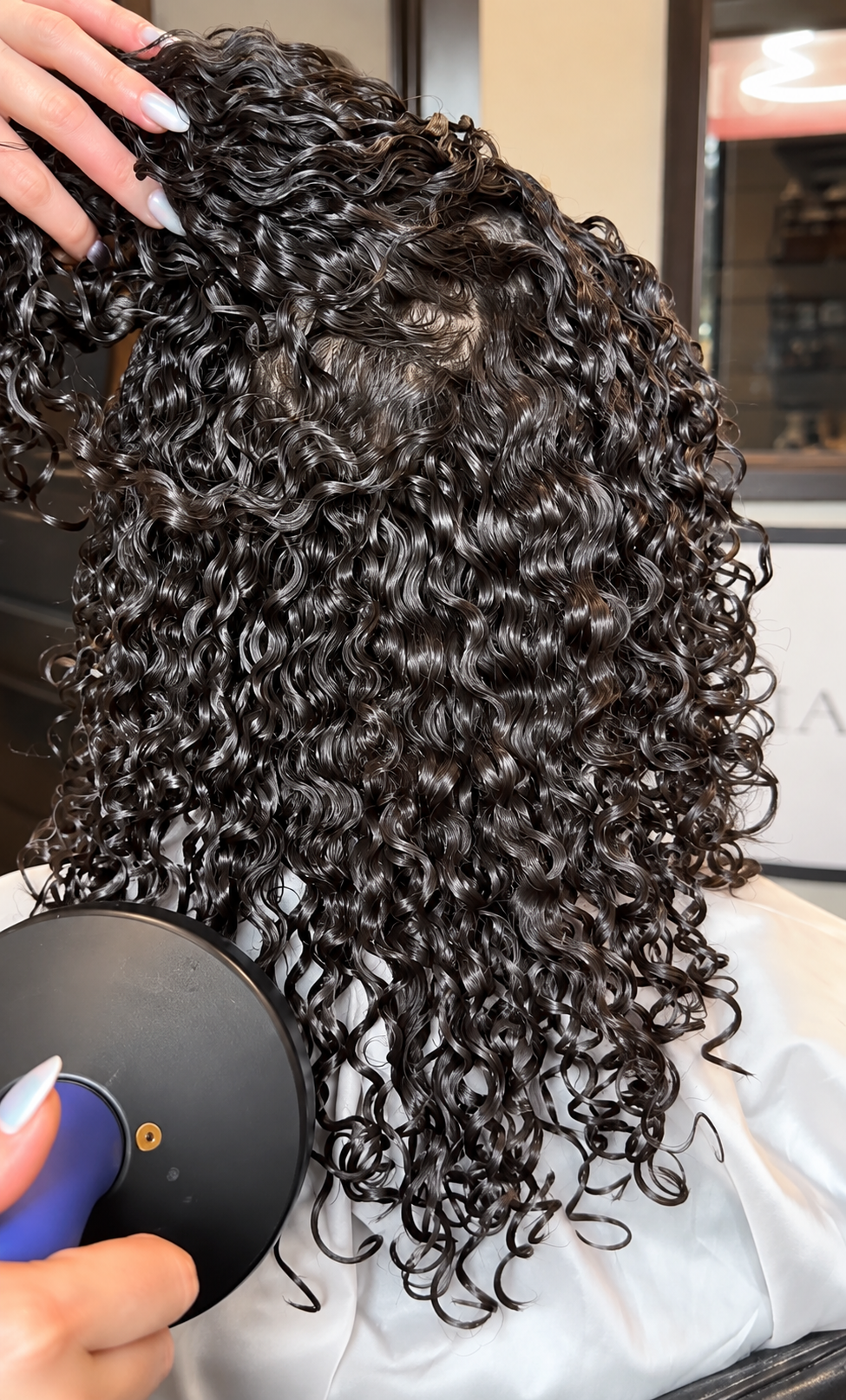 Hand brushing wet, curly dark hair with a detangling brush