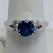 Blue sapphire ring with diamond accents on a white finger holder.