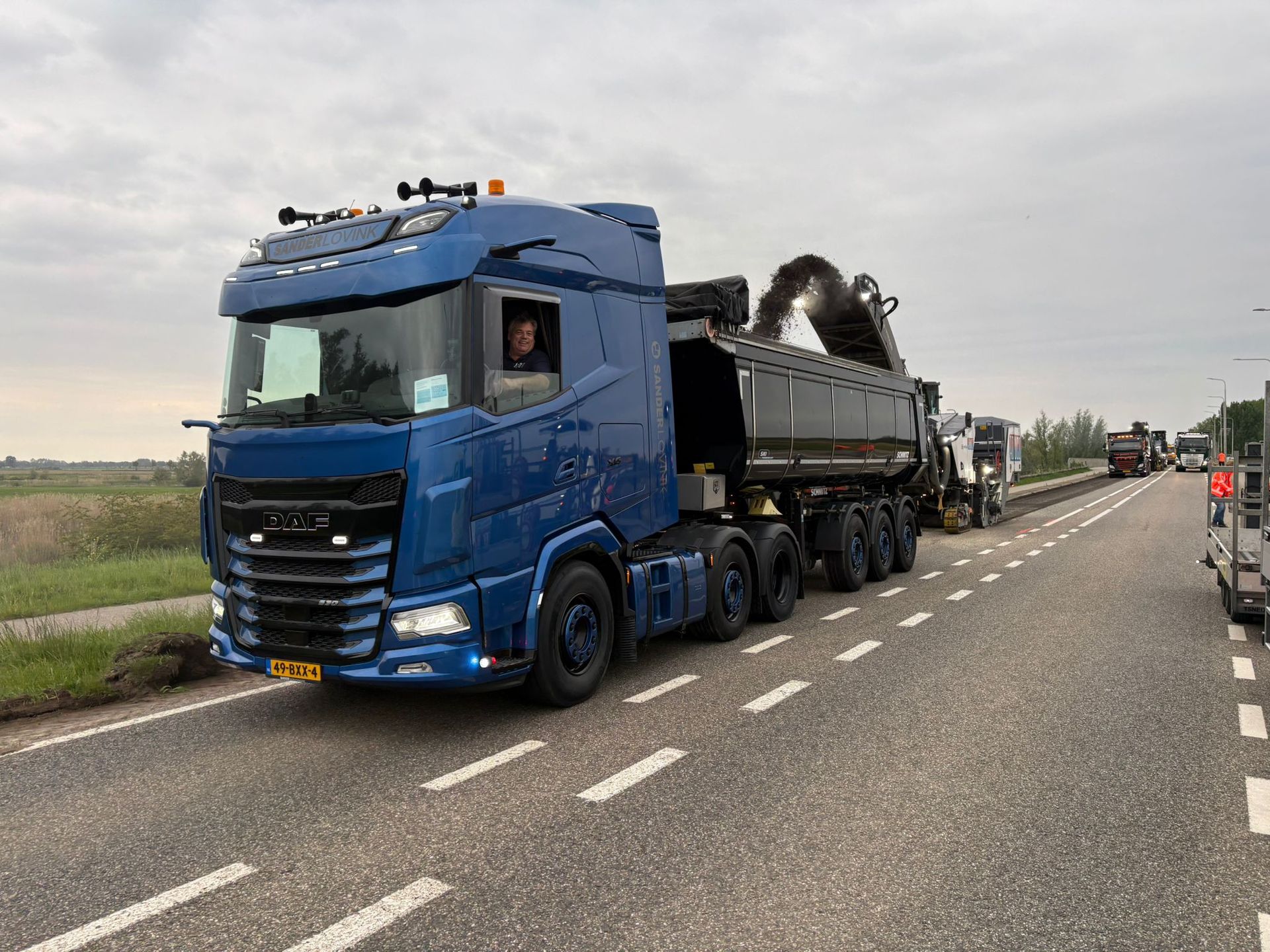 Blauwe vrachtwagen met oplegger op een snelweg langs de weg