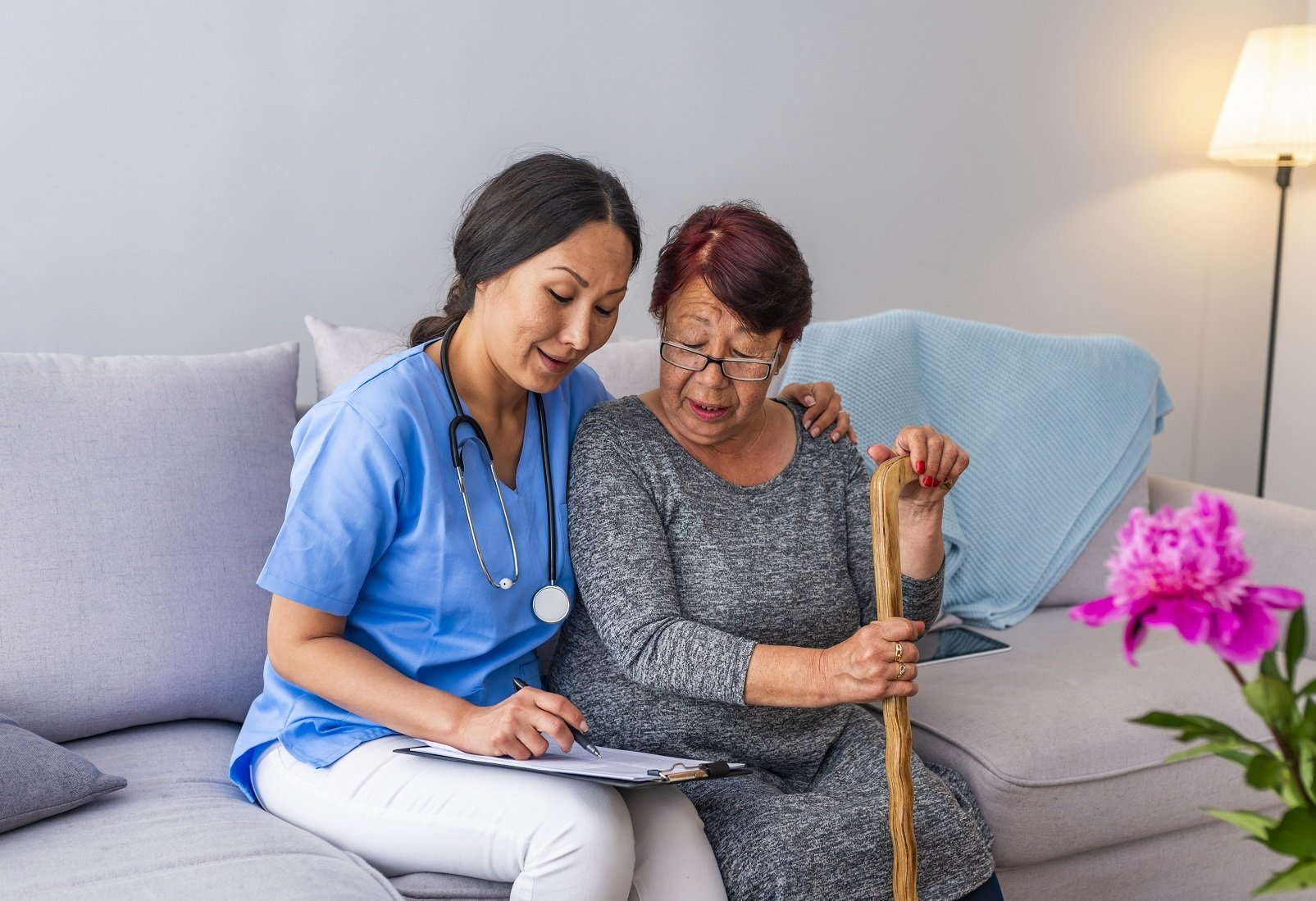 in-home caregiver helping older woman fill out paperwork