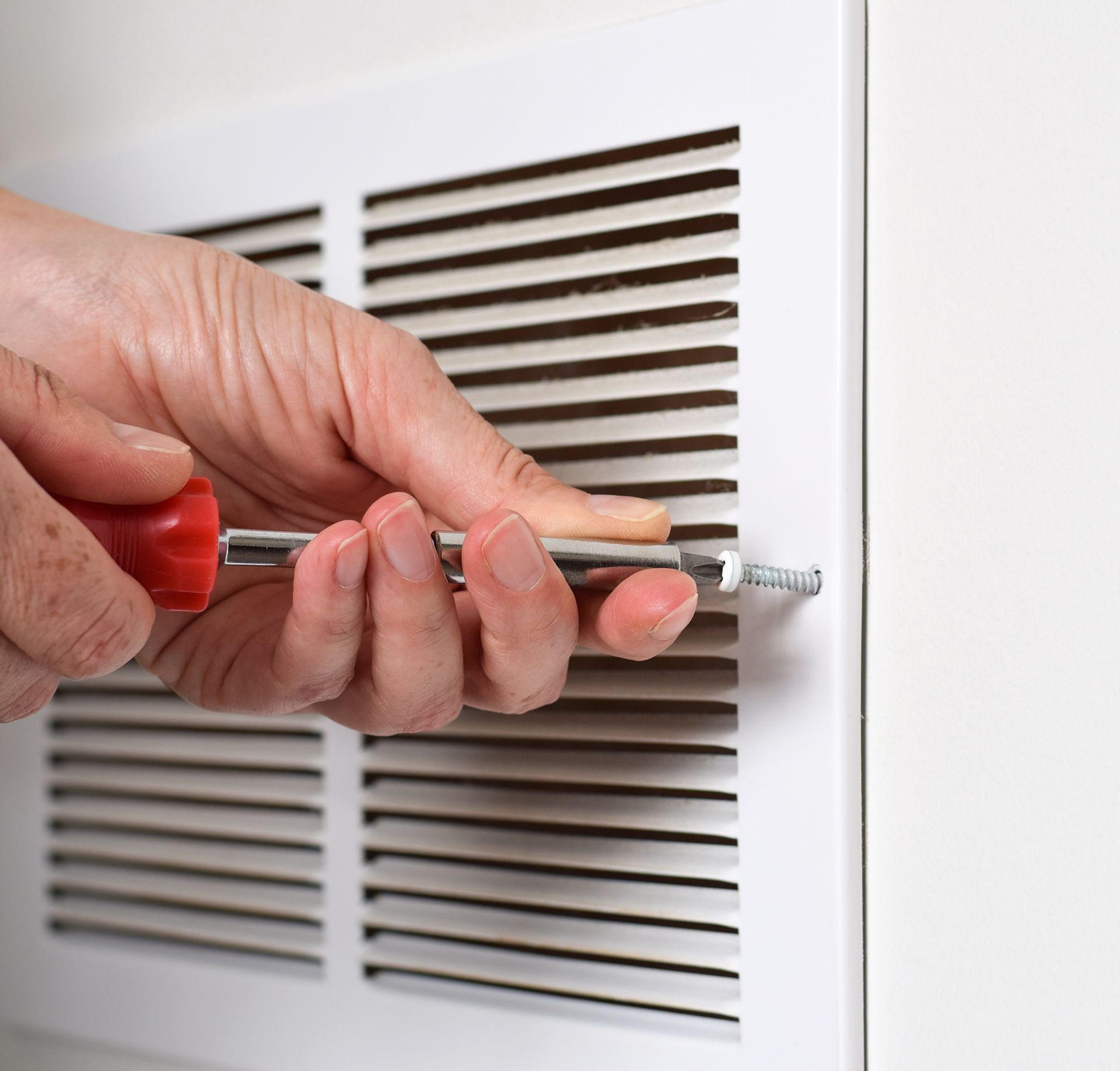 A person is fixing a vent with a screwdriver.
