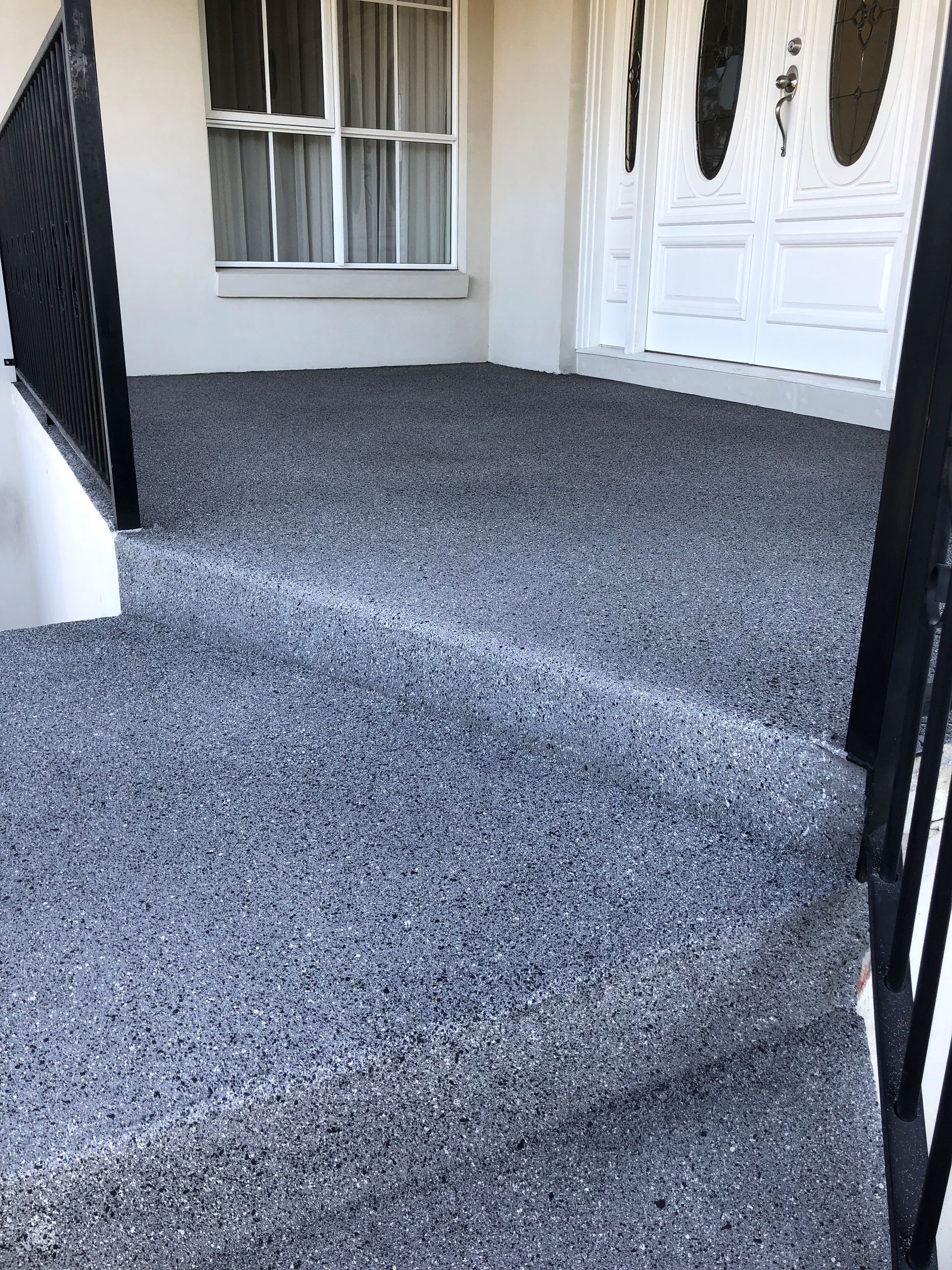 A concrete porch with brick steps leading to it