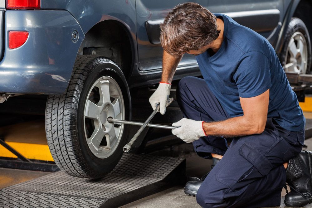 Man Fixing Car Tire With Rim Wrench — Ballina Tyrepro in Ballina, NSW
