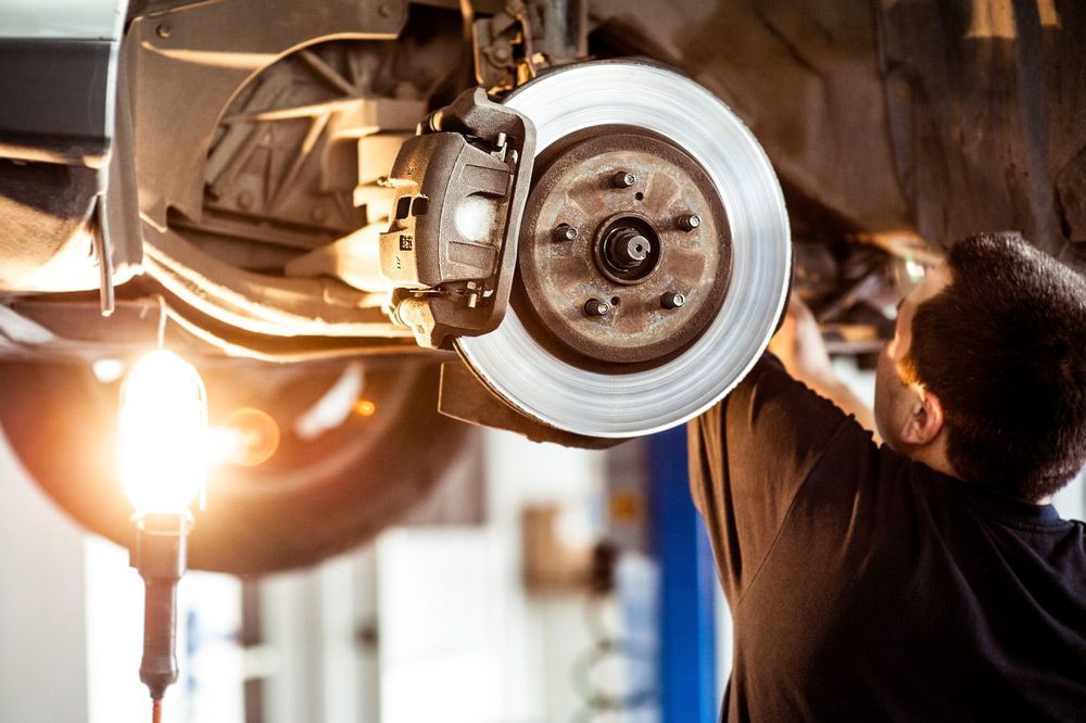 Man Repairing The Car Hanging On The Lift — Ballina Tyrepro in Ballina, NSW