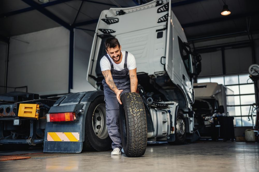 Man Rolling Tire In Order To Change It On Truck — Ballina Tyrepro in Ballina, NSW
