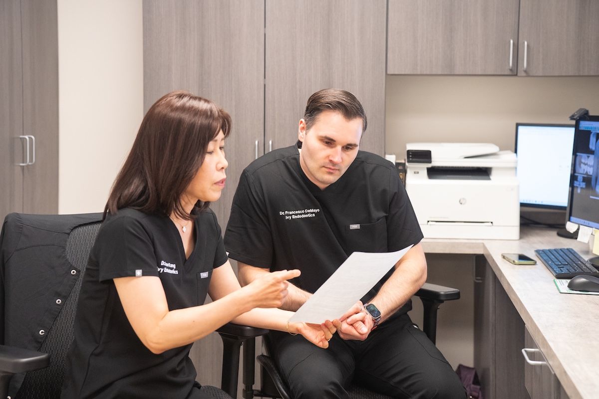 Two coworkers reviewing documents in a modern office, seated beside a computer and printer.