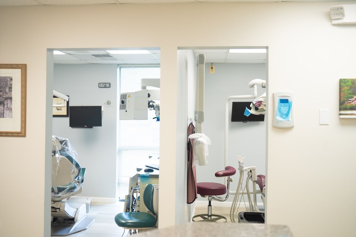 Dental clinic hallway with exam rooms, chairs, and dental equipment visible through open doorways