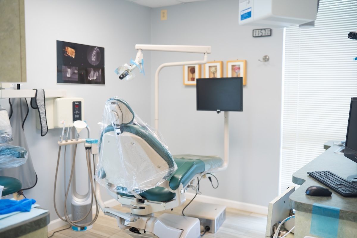 Modern dental exam room with chair, monitors, and tools by a window