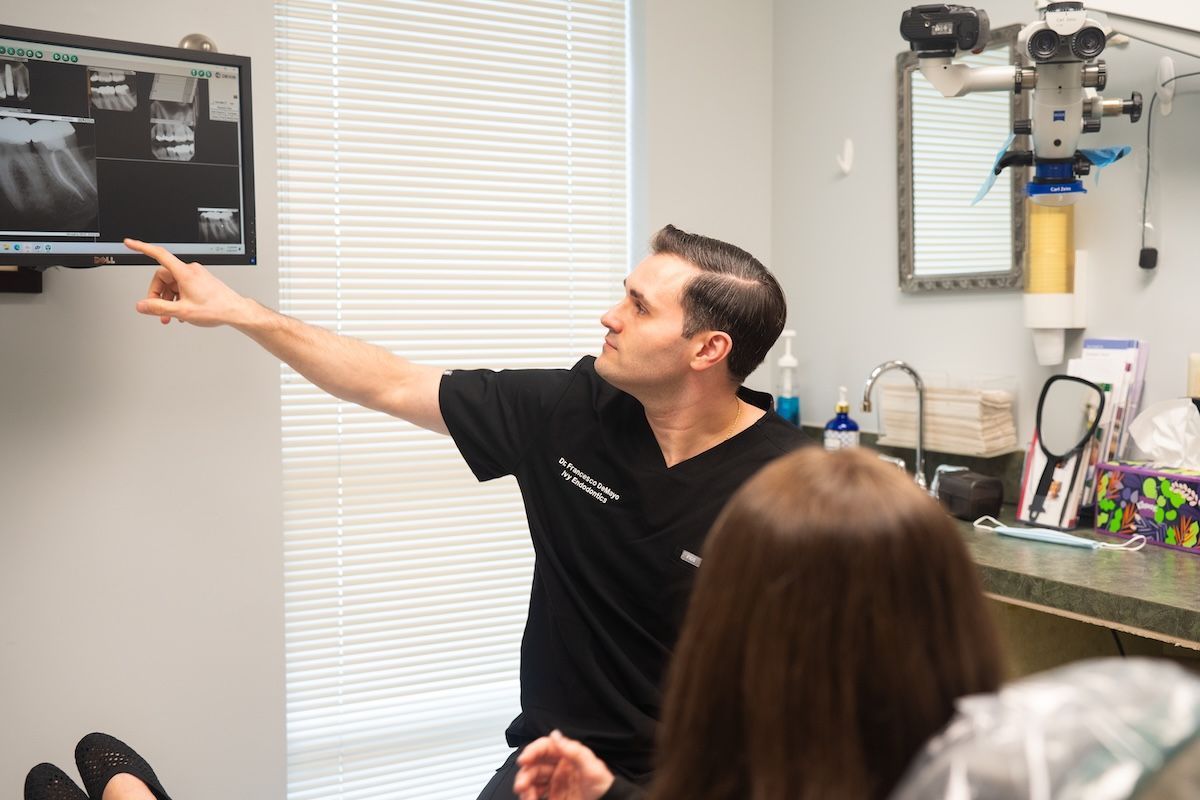 Man points to a wall-mounted medical scan in a clinic while seated people watch