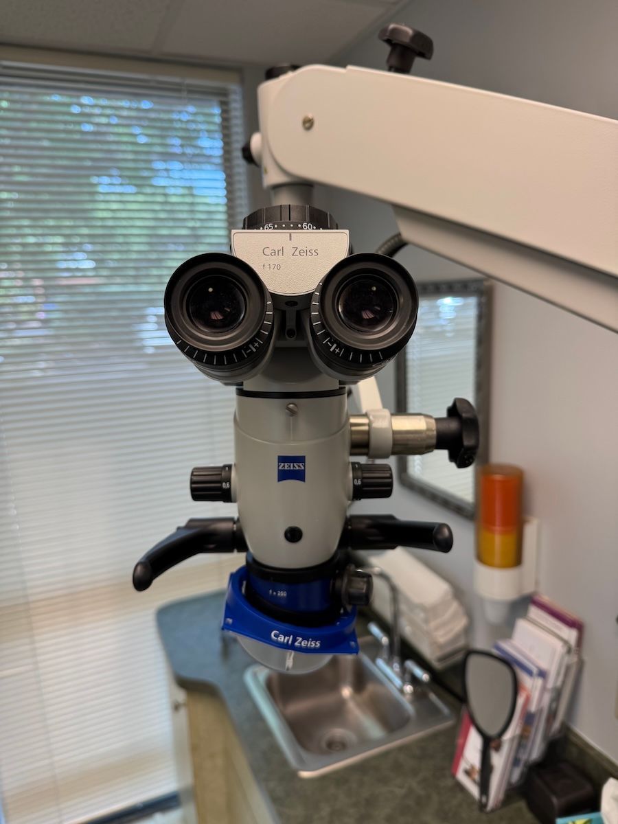 Dental microscope with twin eyepieces over a sink in a clinic room
