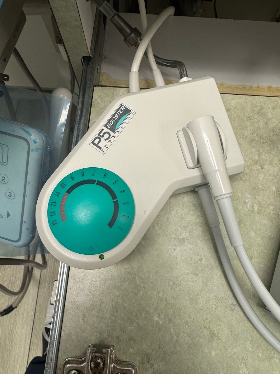 White portable medical device with teal dial and attached probe resting on a counter