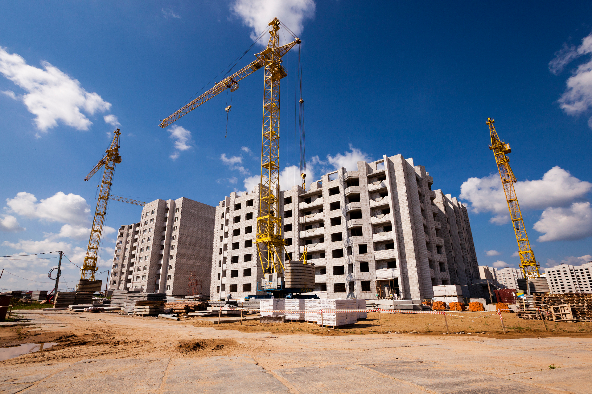 A construction worker is standing in front of a crane on a construction site.