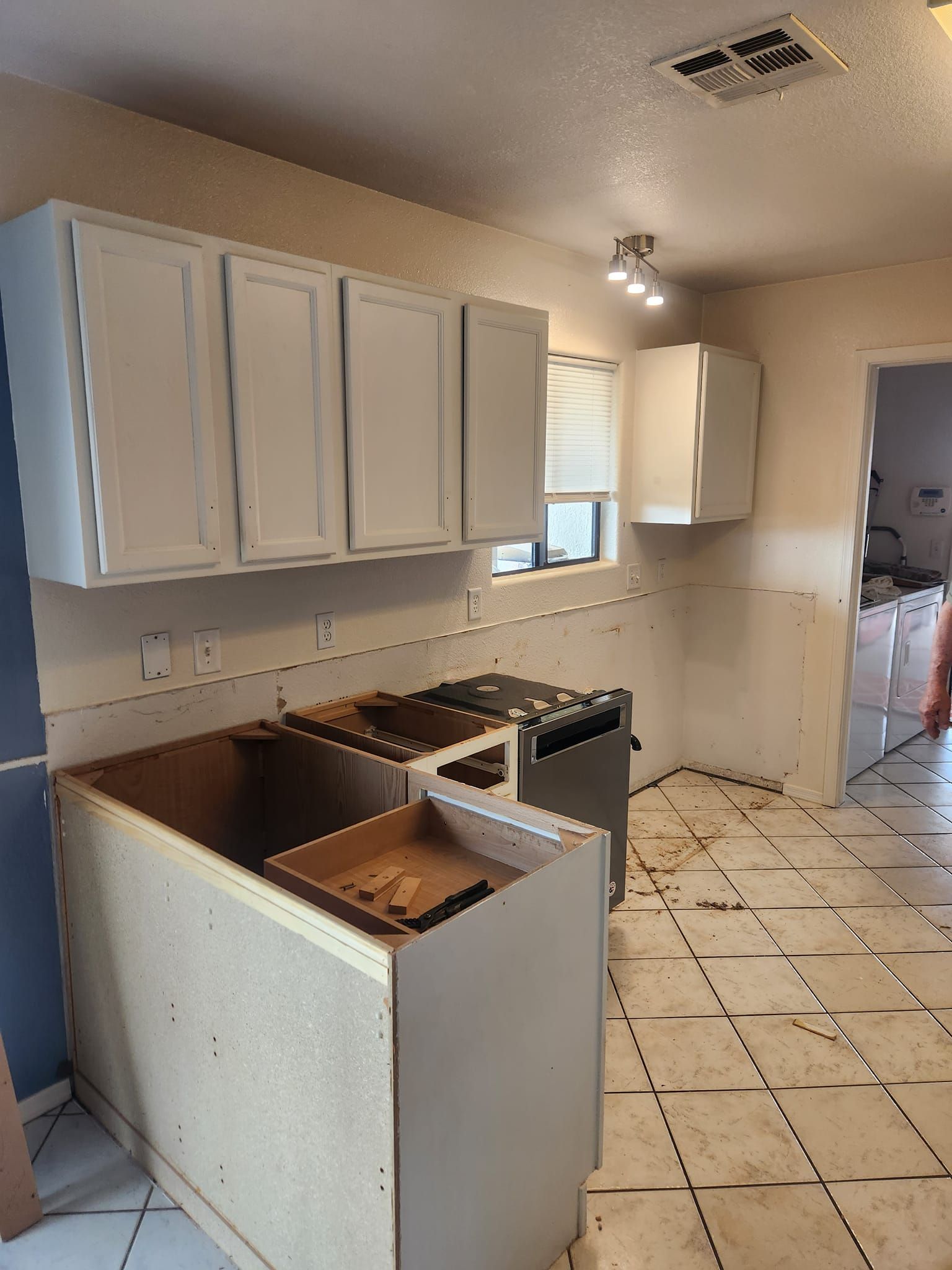 Small kitchen with white cabinets, stove, and a countertop under renovation with exposed surfaces.