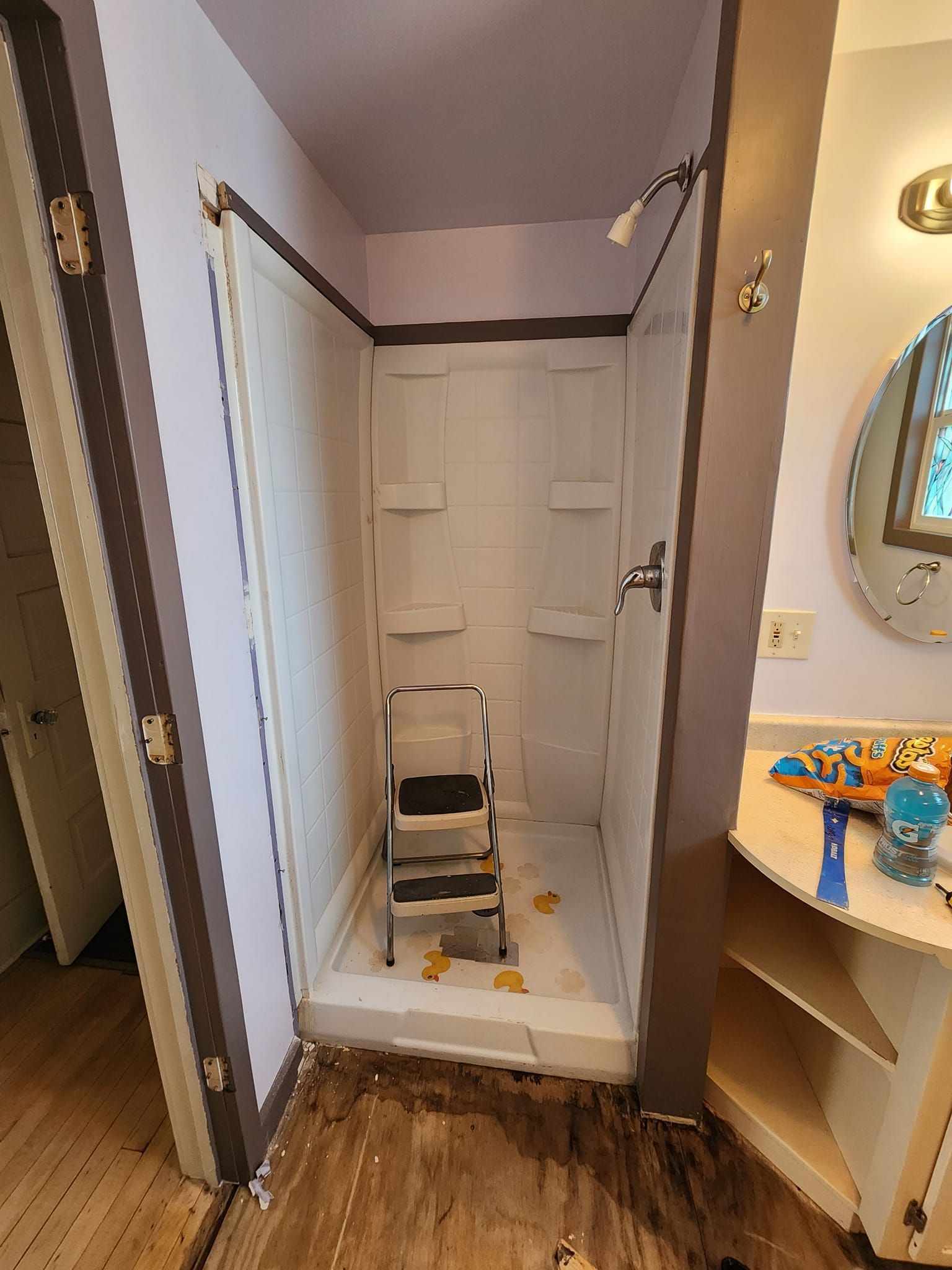 Empty bedroom with wood-look flooring, white walls, closet doors, and a ceiling fan with lights