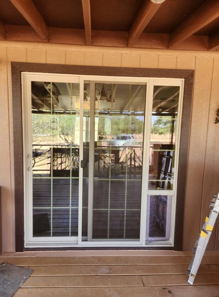 Sliding glass door with white grid frame under a covered wooden patio.
