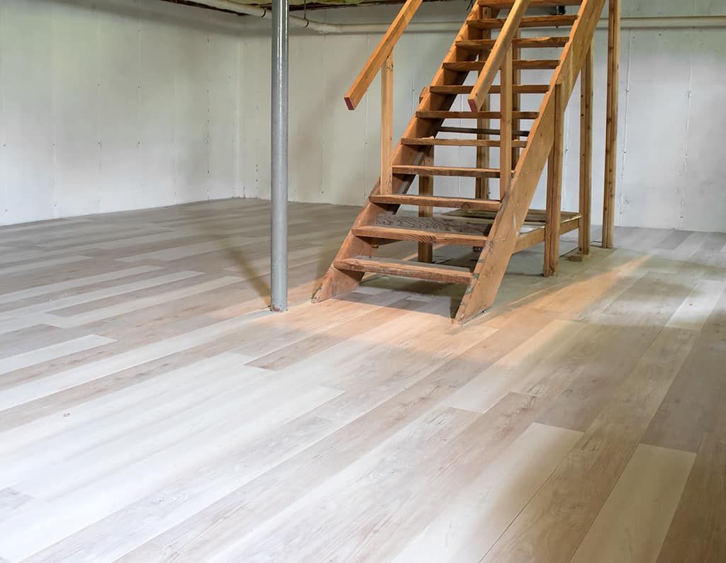 Empty room with light wood floor and a wooden staircase under construction