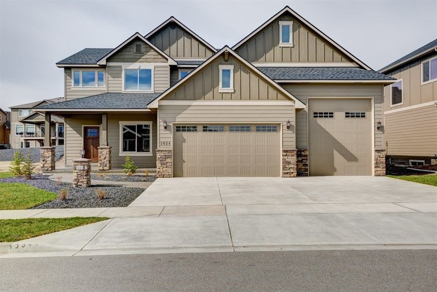 Suburban two-story house with beige siding, a double garage, and a wide concrete driveway
