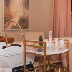 Cozy bedroom with a white bassinet, bedside cart, and pink curtains in warm light
