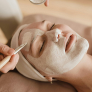 Facial spa treatment with a cream mask and brush applied to a reclining client