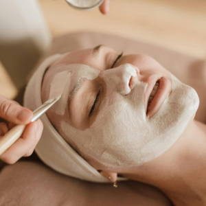 Facial spa treatment with a cream mask and brush applied to a reclining client