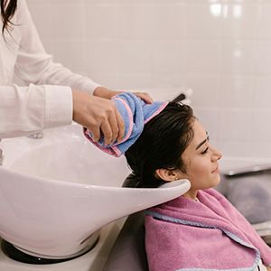Massage therapist pouring oil onto a client’s back during a spa treatment