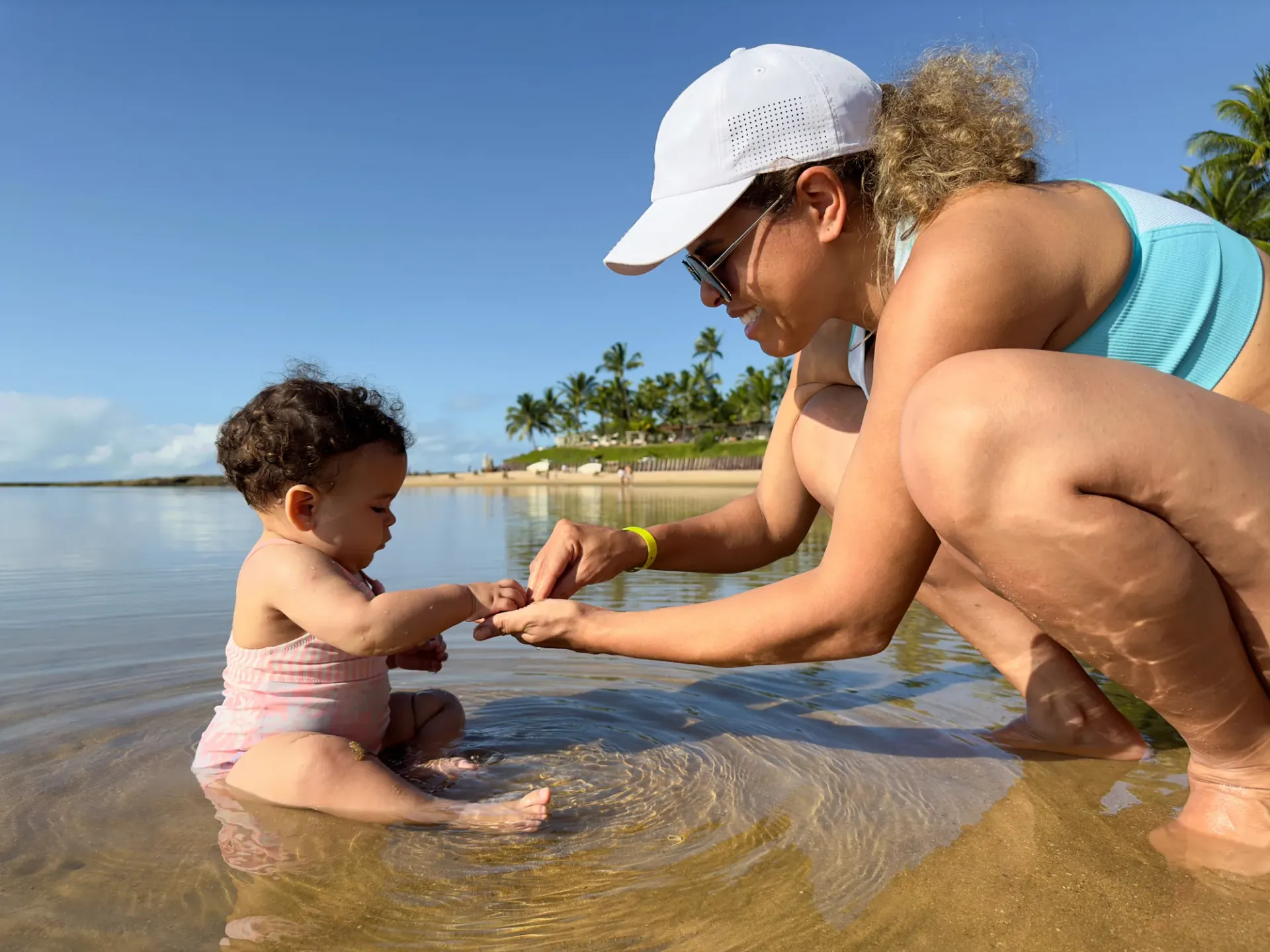 Uma mulher e um bebê estão brincando na água na praia.