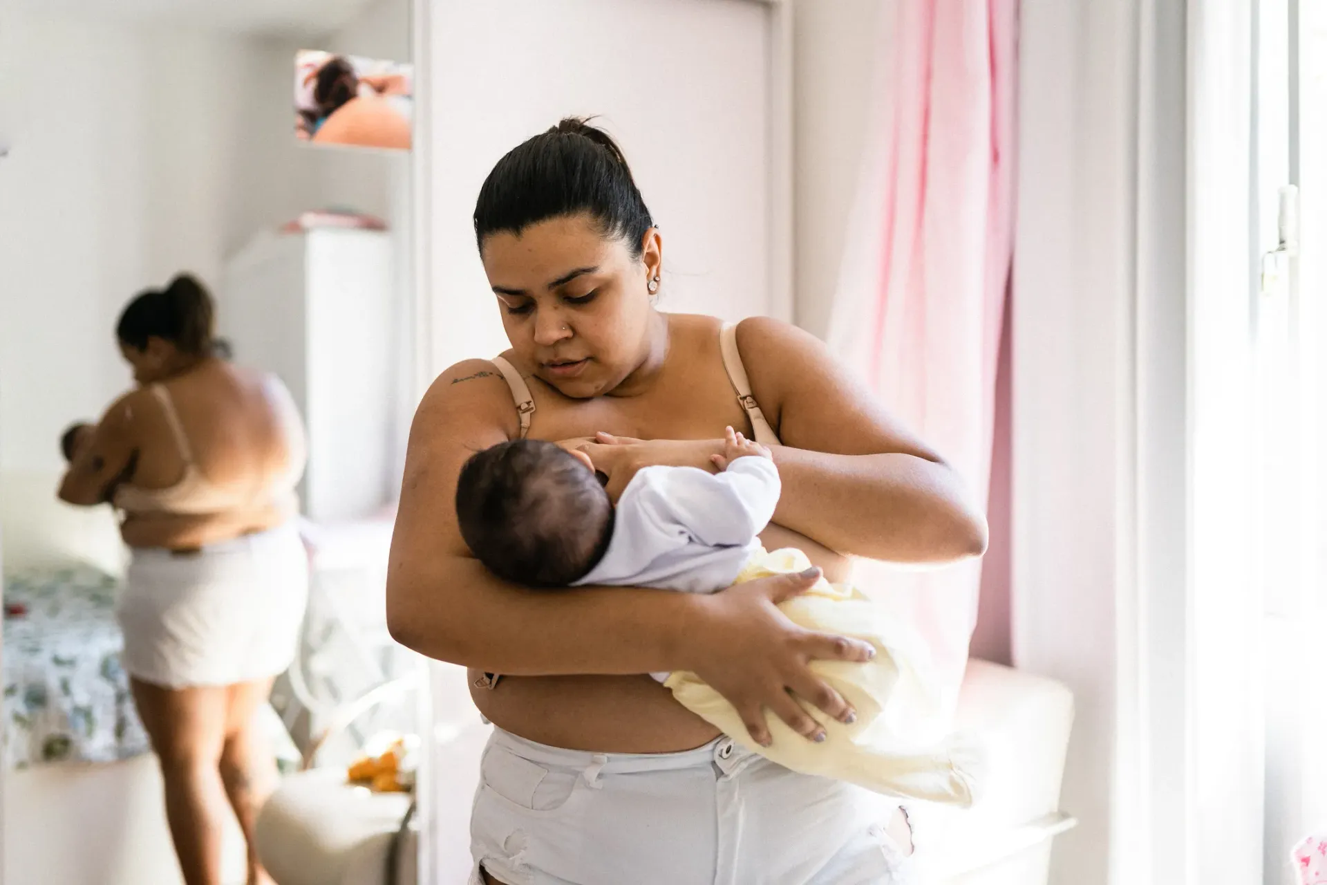 Uma mulher está segurando um bebê nos braços em frente a um espelho.
