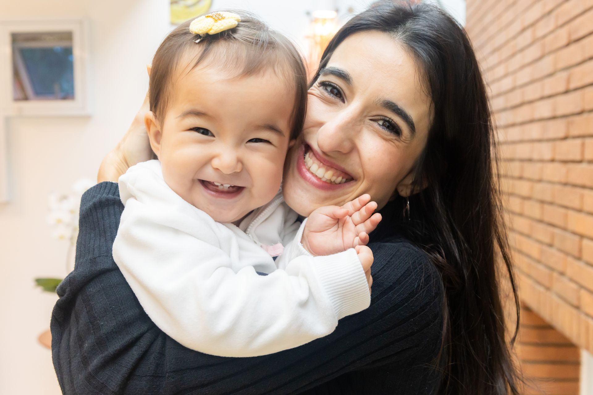 Uma mulher está segurando um bebê nos braços e sorrindo.