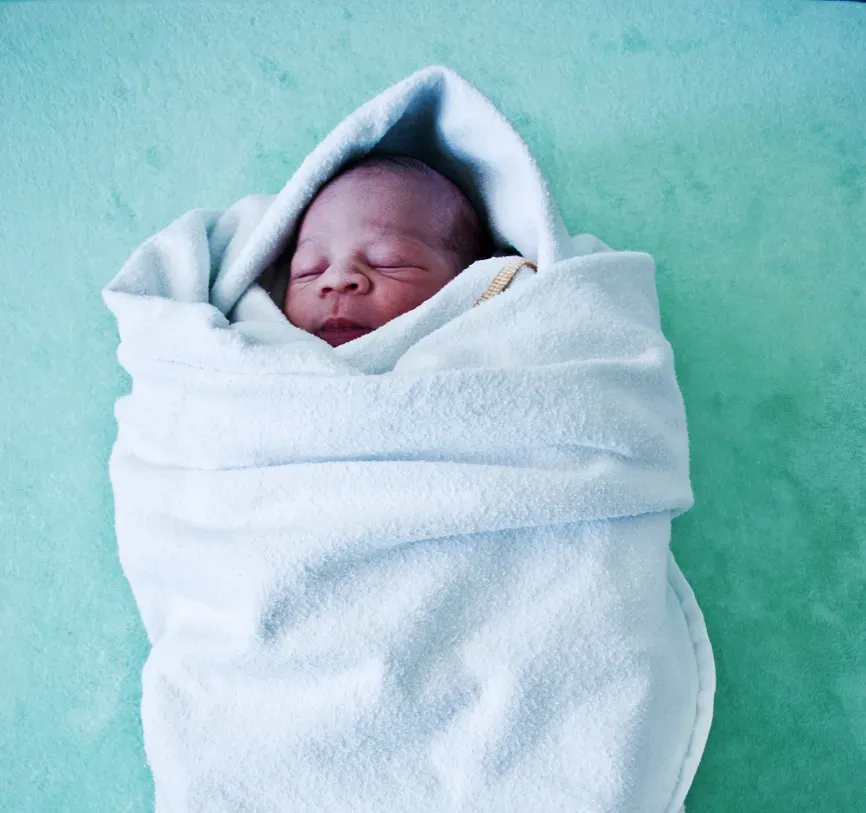 Um bebê recém-nascido está enrolado em um cobertor branco