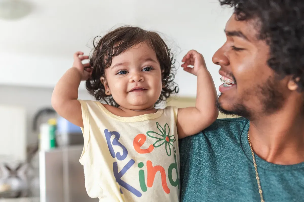 Um homem está segurando uma menina que está vestindo uma camisa