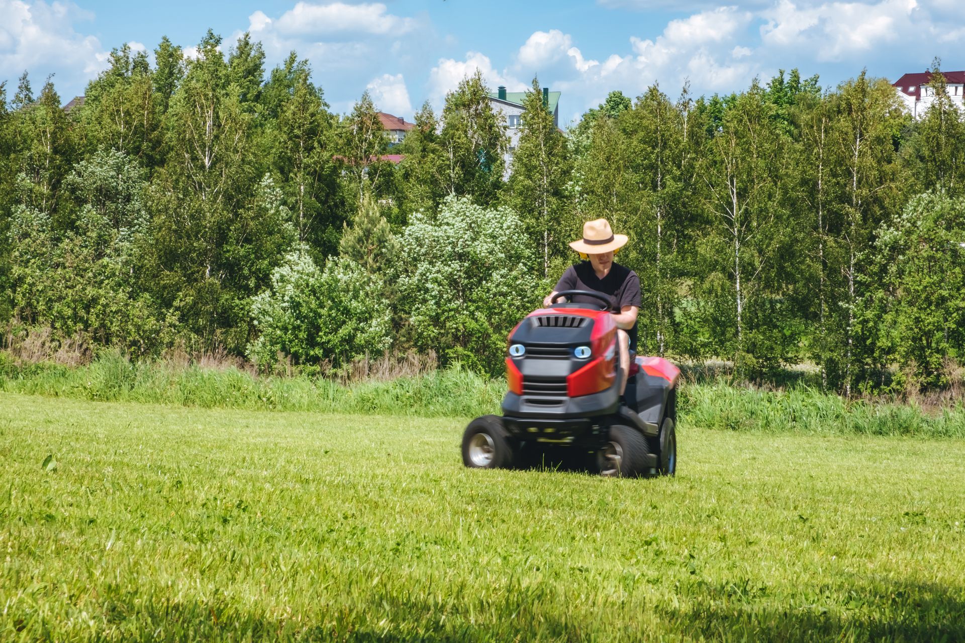 Man on lawn tractor mowing the lawn in the backyard.