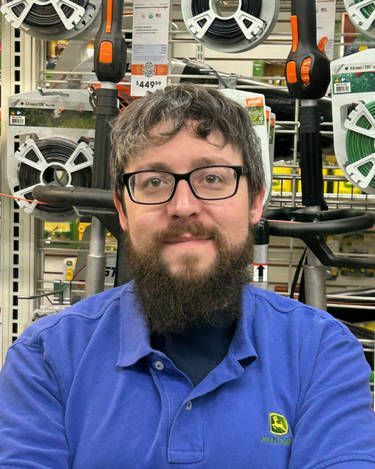 A man with a beard and glasses is wearing a blue shirt in a store.