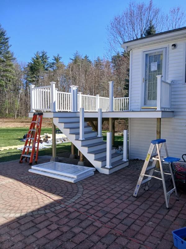A white house with a deck and stairs being built.