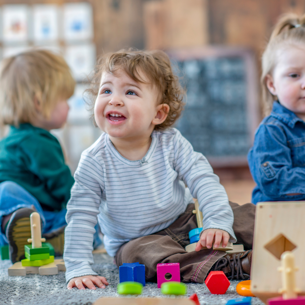 Three children are sitting on the floor playing with toys.