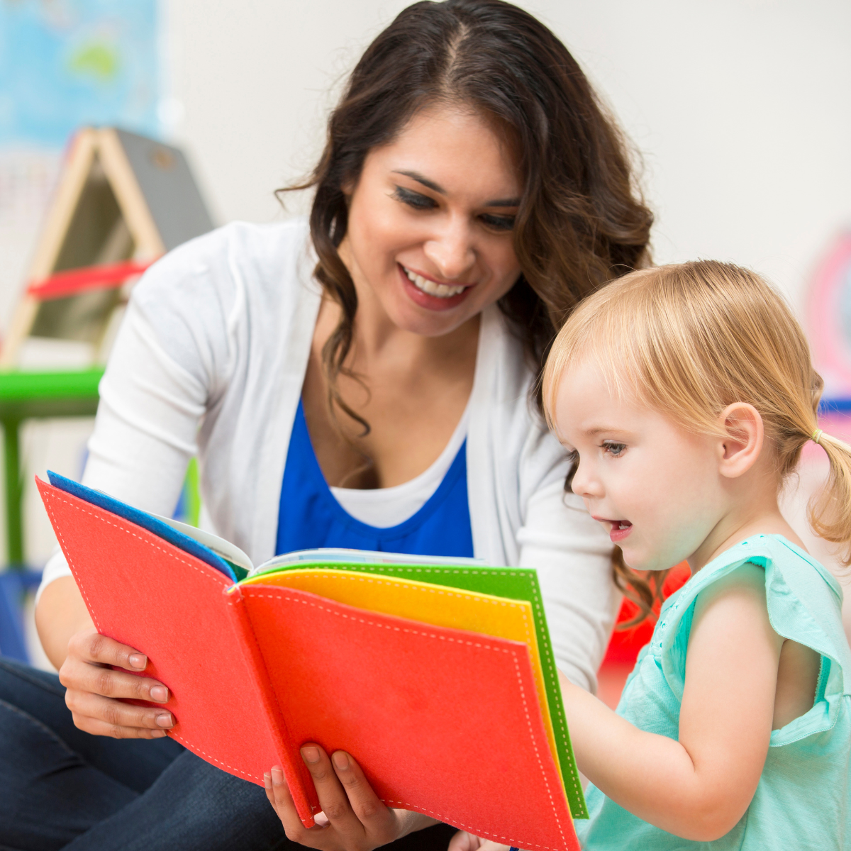 A woman is reading a book to a little girl.
