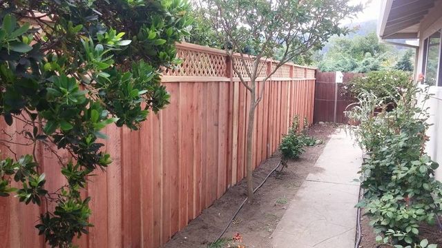 A wooden fence along a sidewalk next to a house