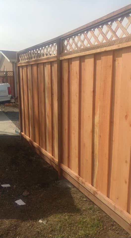 A wooden fence with a lattice top is in the backyard of a house.