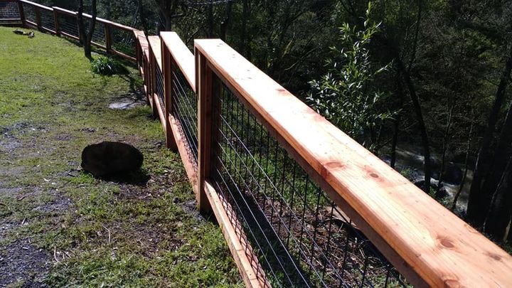 A wooden fence surrounds a grassy area with trees in the background