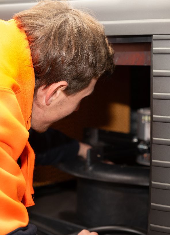 A Man in An Orange Hoodie Is Working on A Machine — BJ Heating & Cooling in South Albury, NSW