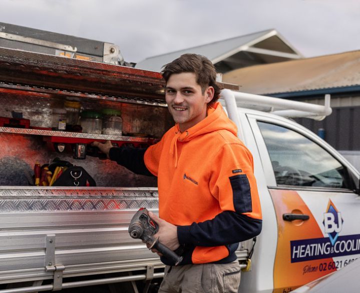 A Man is Standing Next to a Heating and Cooling Truck — BJ Heating & Cooling in Beechworth, VIC